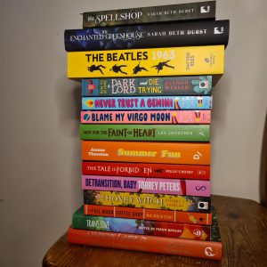 Vakantiesouvenir boeken: een stapel van 14 boeken waarvan je de titels op de rug ziet.