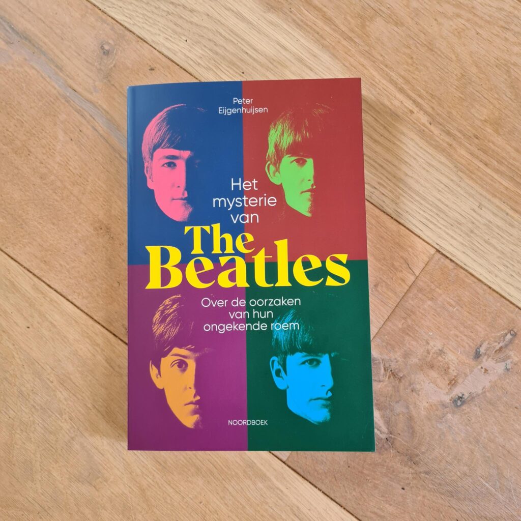 Boek Het mysterie van The Beatles van Peter Eijgenhuijsen op een houten vloer.