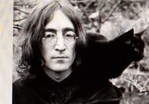 Zwart-wit foto van John Lennon met een zwarte kat op zijn schouder.
