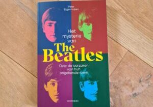 Boek Het mysterie van The Beatles van Peter Eijgenhuijsen op een houten vloer.